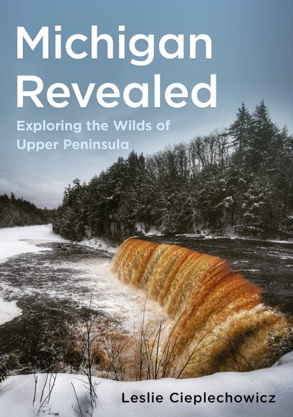 Book cover of 'Michigan Revealed: Exploring the Wilds of Upper Peninsula' with a snowy landscape and waterfall.