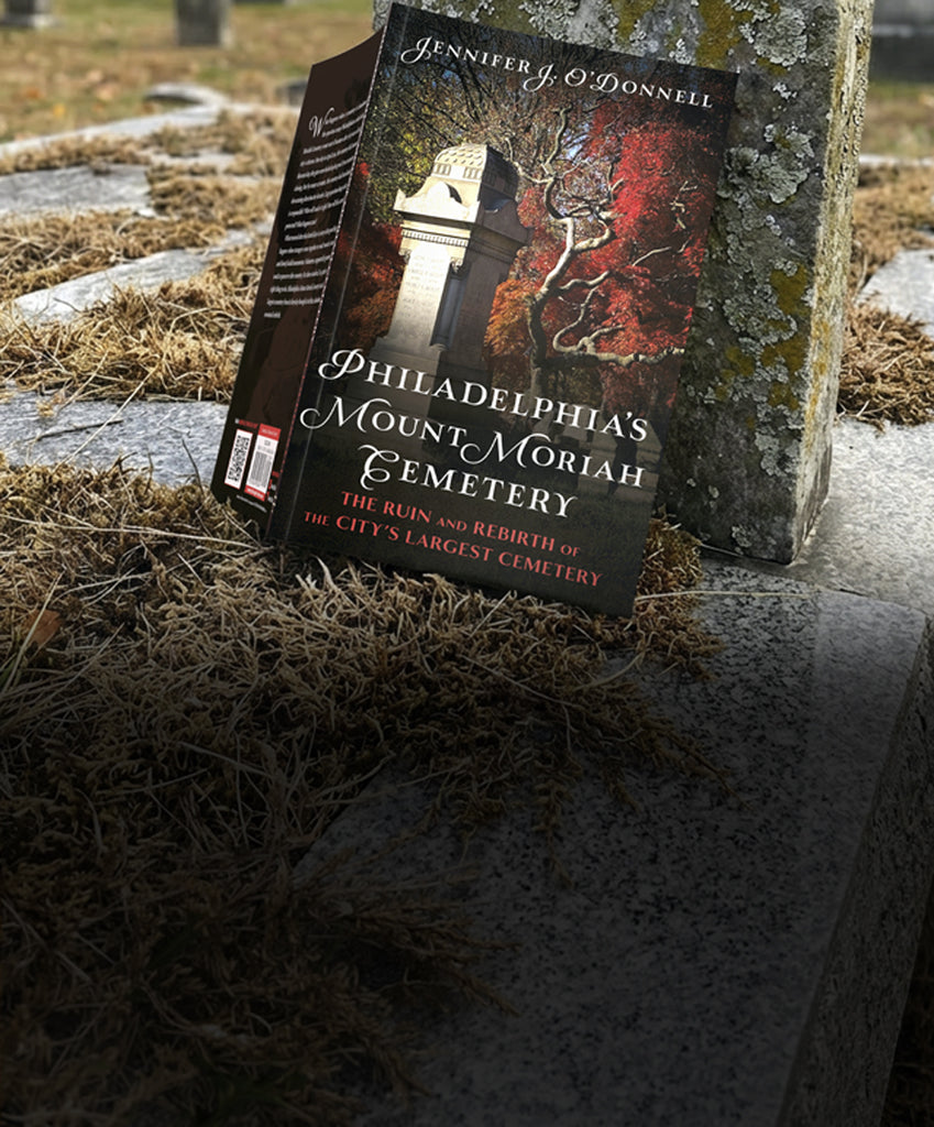 Book titled 'Philadelphia's Mount Moriah Cemetery' on a gravestone in a cemetery.